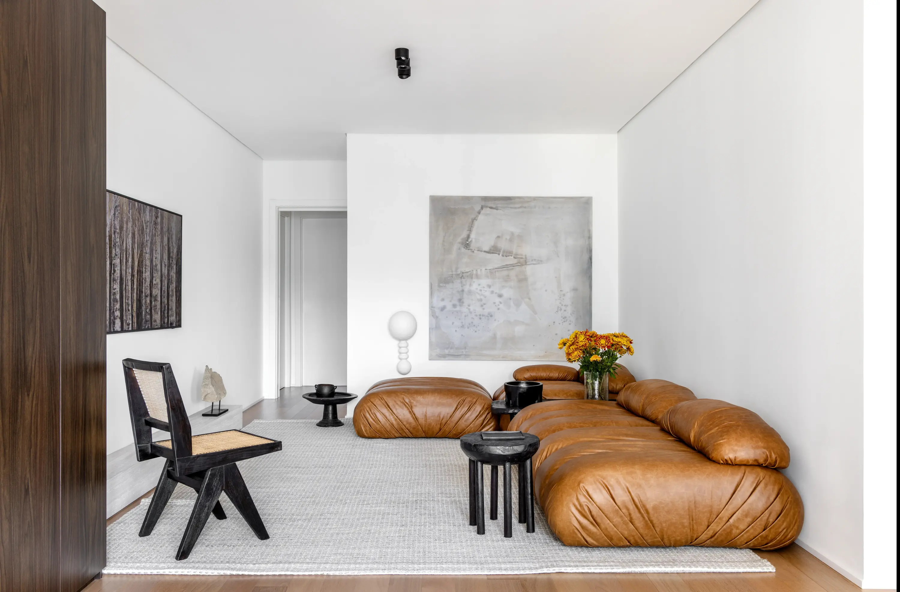 Sala de estar do Apto Luz com sofá caramelo e decoração minimalista - Studio Guilherme Garcia