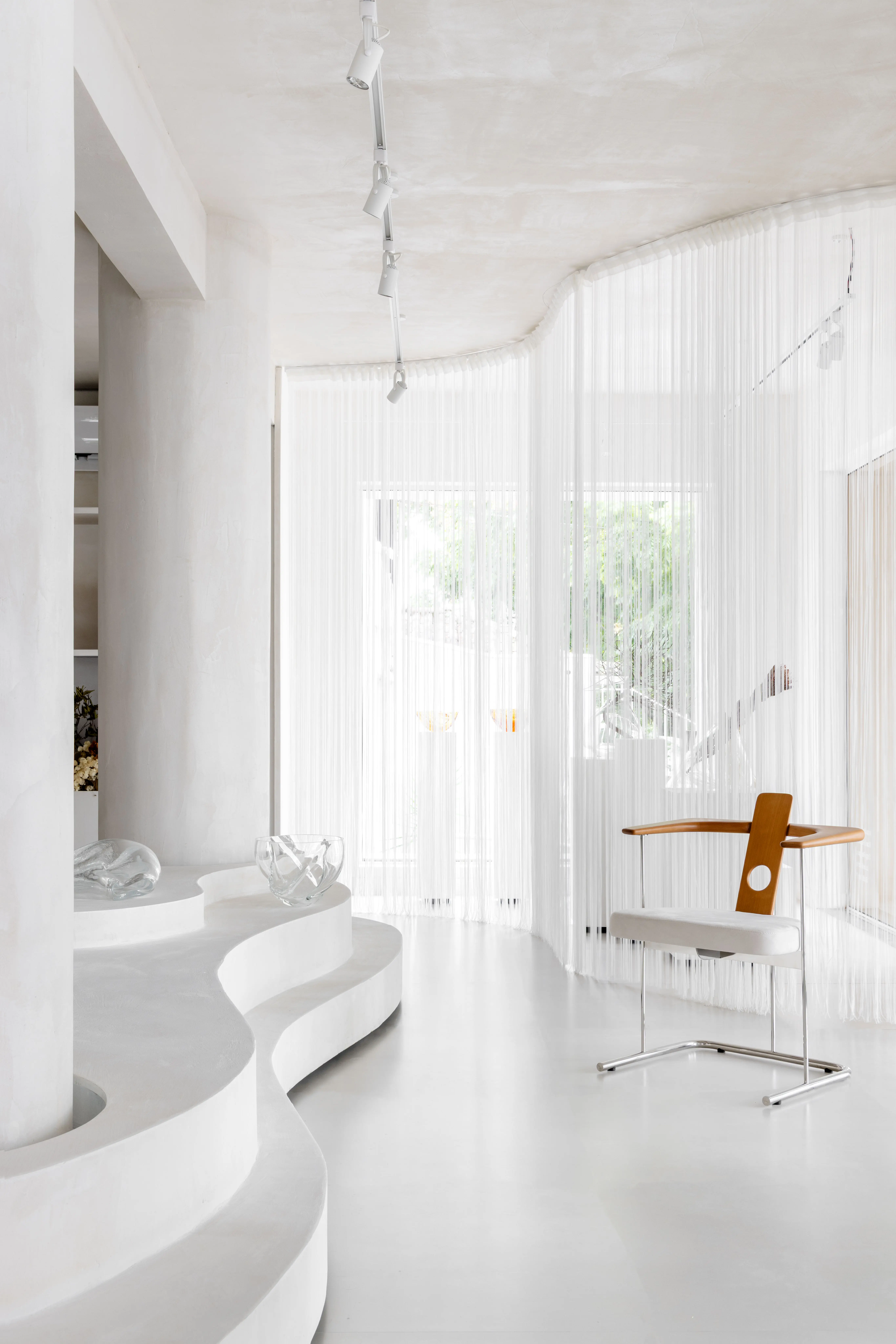 Sala integrada e iluminada no projeto Tempo Casa por Studio Guilherme Garcia, com cortina leve e acabamento escultural em branco