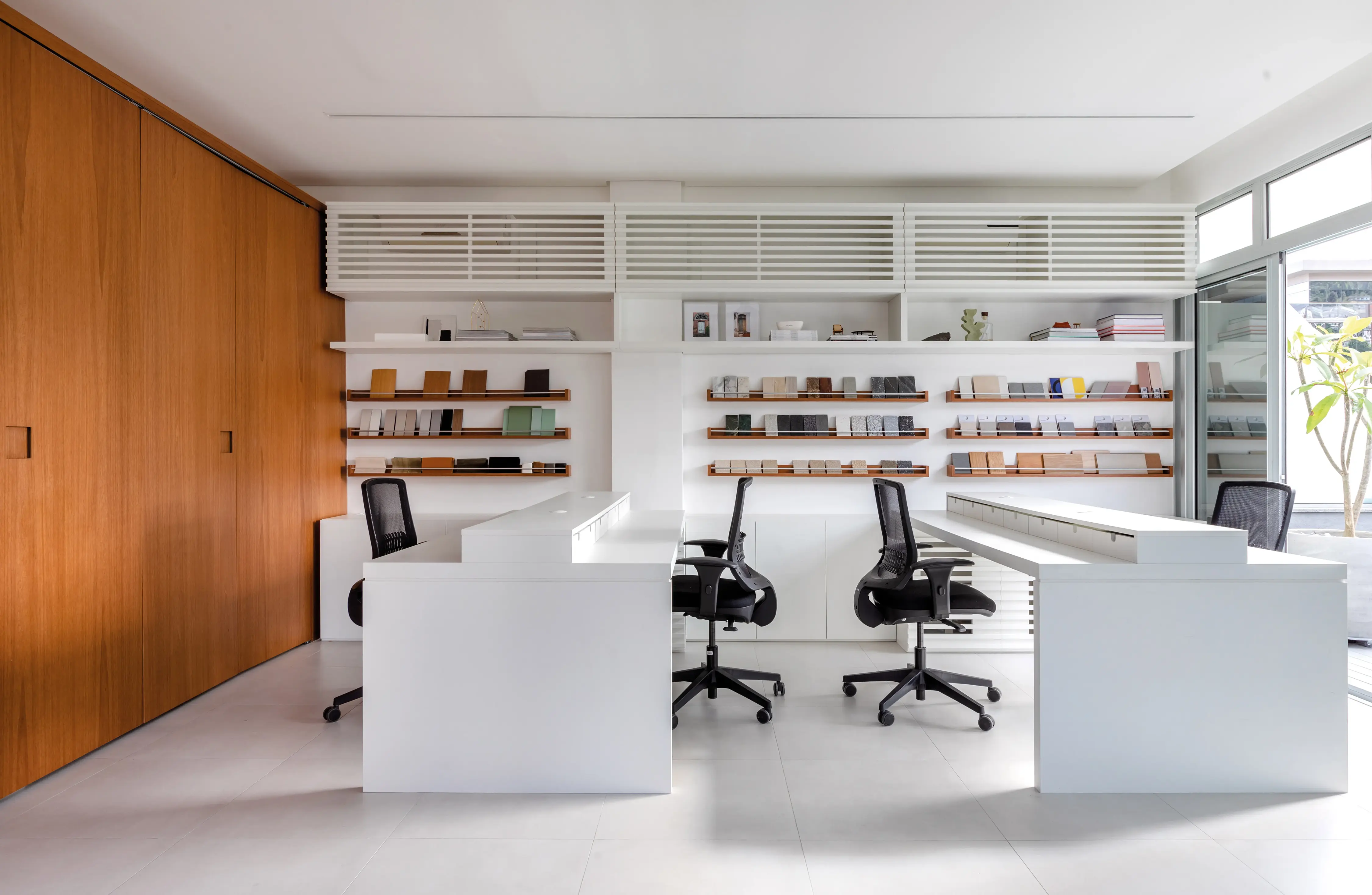 Estação de trabalho do Studio Guilherme Garcia com estantes e cadeiras ergonômicas
