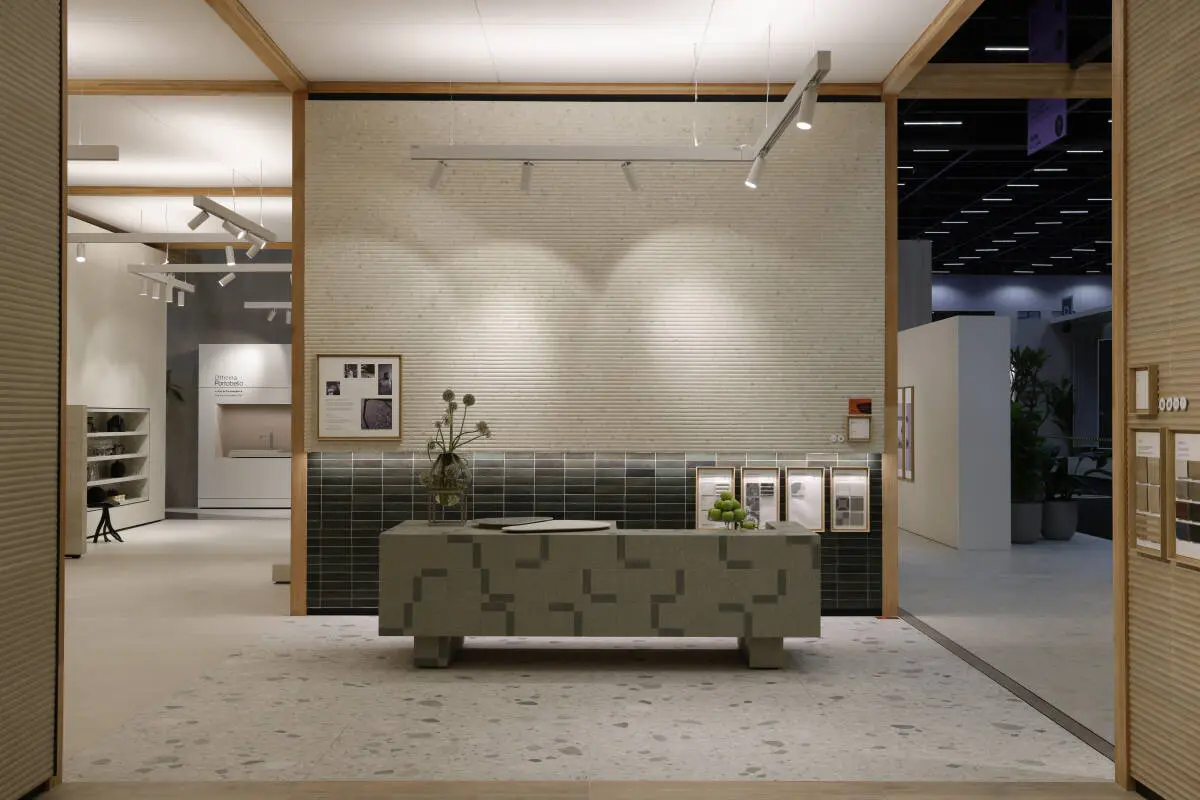 Ambiente expositivo da Portobello na Revestir 2025 com cenografia minimalista, balcão em revestimento geométrico e parede com texturas em porcelanato.